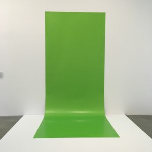 Liz Deschenes, "Green Screen #4", image courtesy the artist and ICA Boston. From wall text: "Green screens are commonly used in television, film and video game production. Deschenes created this interpretation by mounting a 15-foot long monochrome photograph to Duratrans, a material used for commercial photography displays. Green screens are typically invisible to the viewers, but Deschene's is both a photograph and a backdrop. Dating to the 1930s, the technology was initially developed for film using blue backdrops, but with the advent of digital technologies green became the dominate color for special effects. As darker skin tones do not composite well on blue screens, the move to green screens also signaled increased visibility of African-Americans in the cultural and entertainment realm. With this body of work, Deschenes offers a subtle commentary on the changing perceptions of race and its relation to the history of film and photographic technologies."